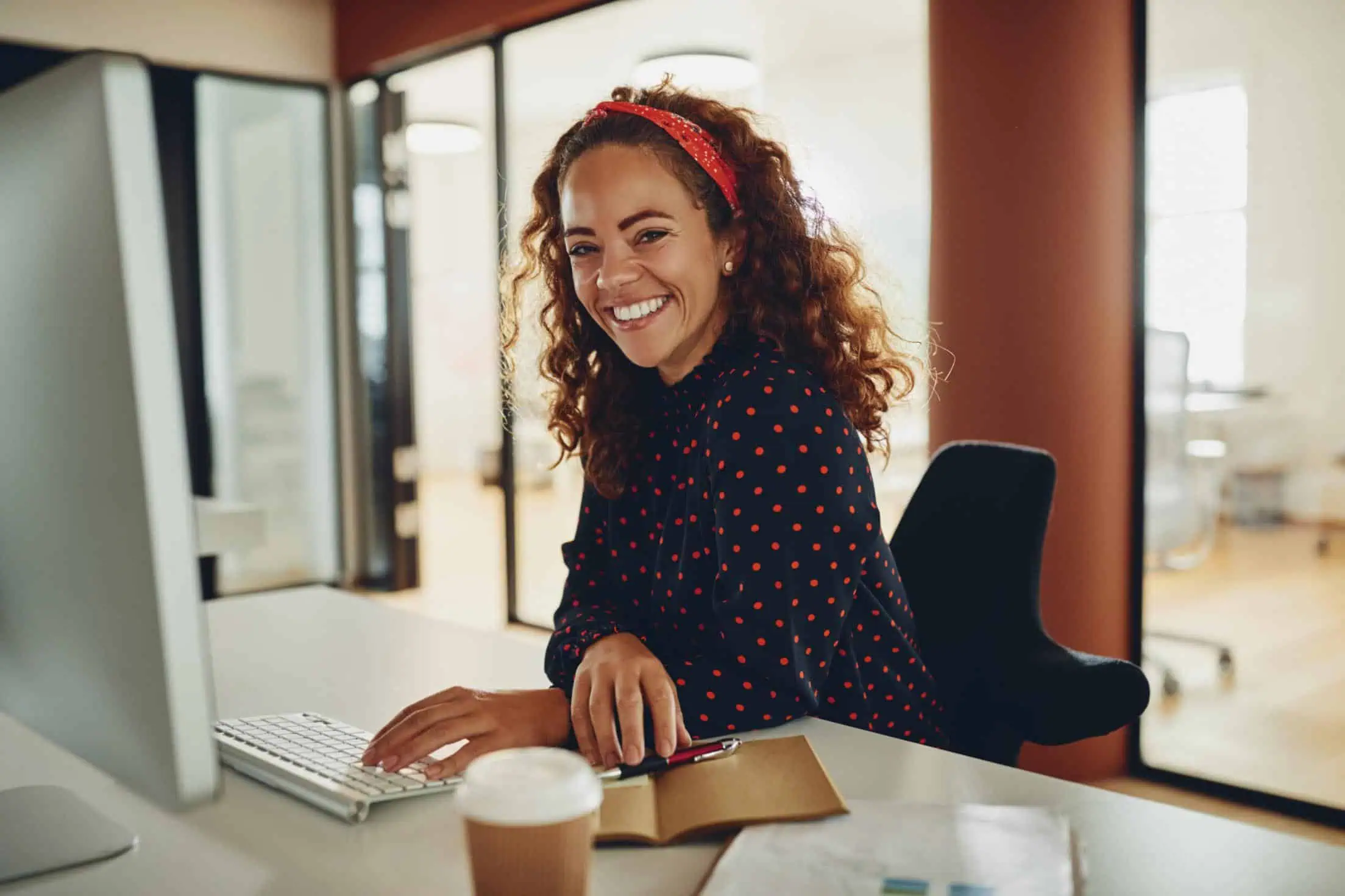 Empresaria en su escritorio con una sonrisa delante del ordenador