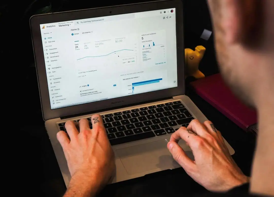Persona analizando datos en Google Analytics desde una computadora portátil, con gráficos de rendimiento y estadísticas en pantalla.