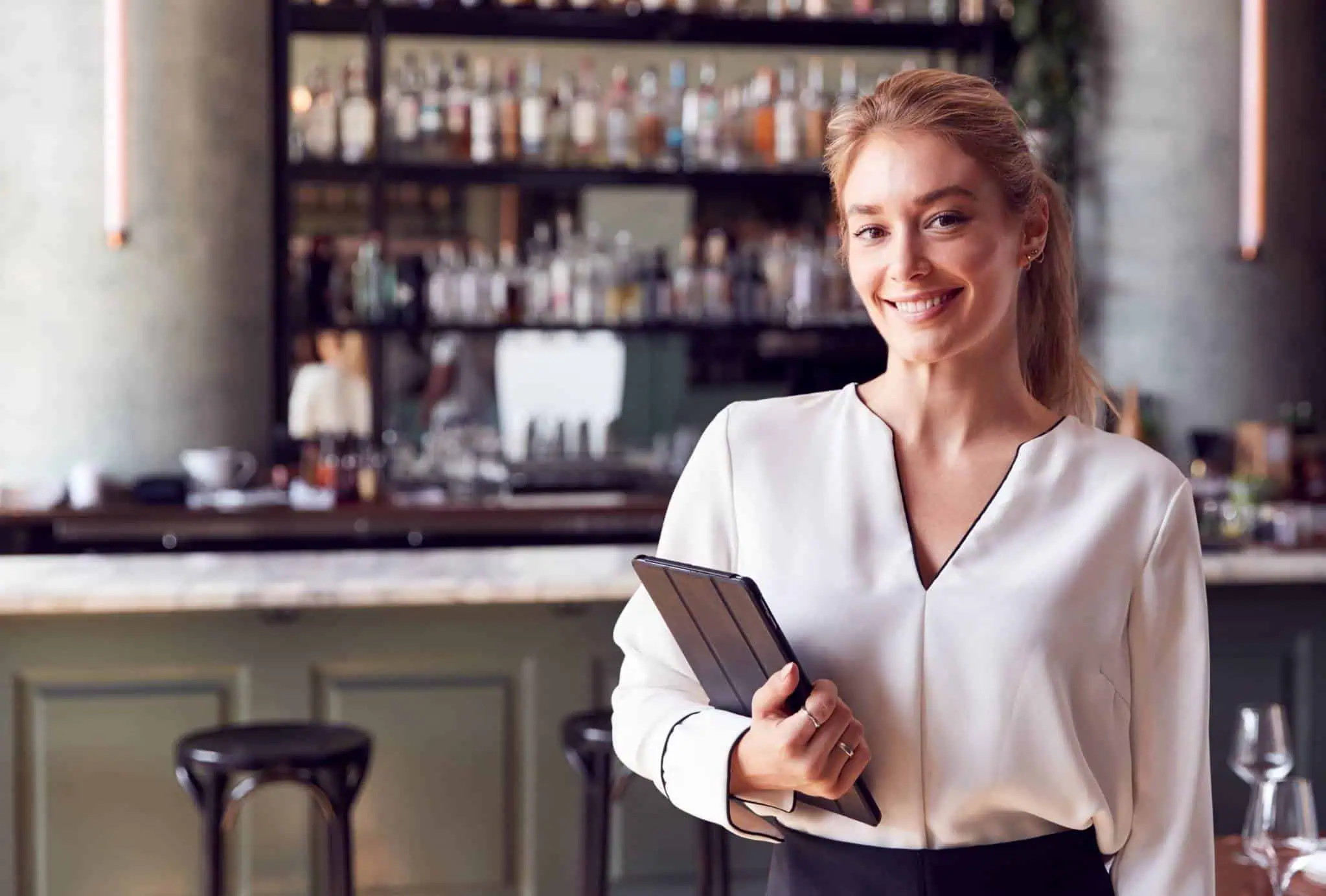 Propietaria de un restaurante sonriendo mientras gestiona su negocio con una tablet